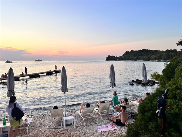 Tramonto dorato sulla spiaggetta di Ciolo, relax e mare calmo.