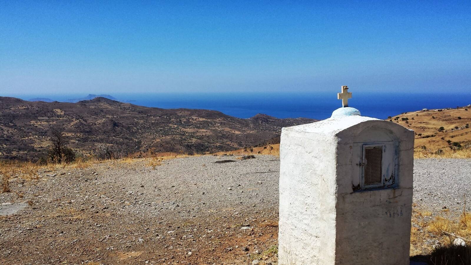 Sosta lungo la strada di Creta: un piccolo tabernacolo bianco e il mare all'orizzonte.