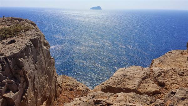 Dalla scogliera, il mare infinito e un'isola all'orizzonte: meraviglia pura.