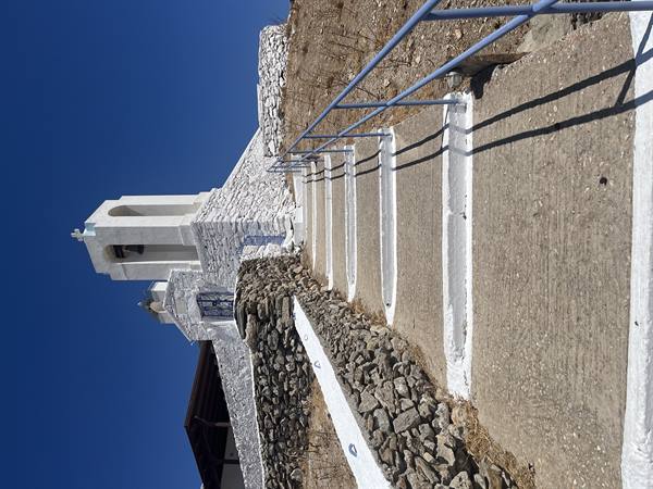 Sotto il cielo azzurro, su per i gradini verso la piccola chiesa bianca.