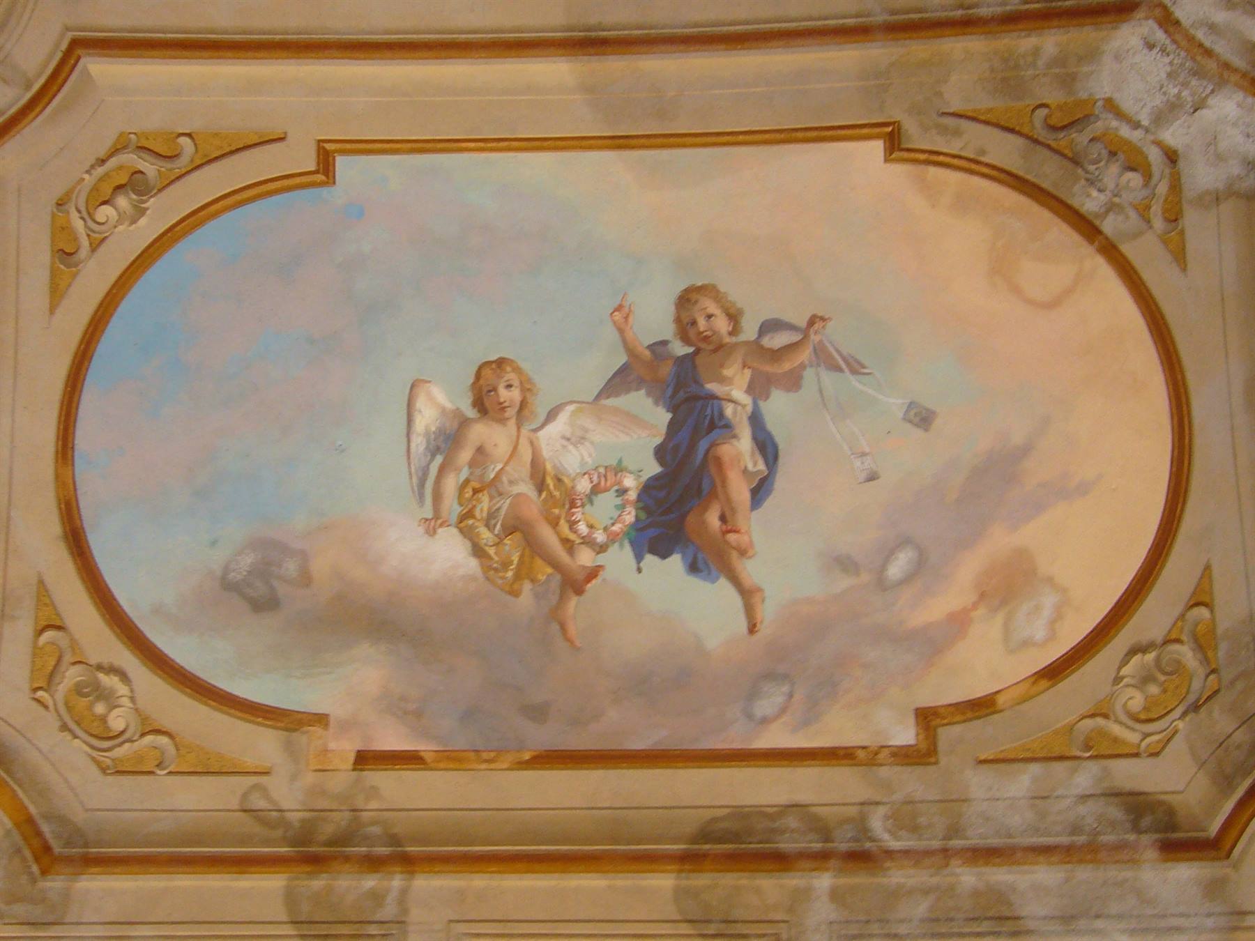 Affresco con due angioletti su nuvole in cornice ovale dorata
