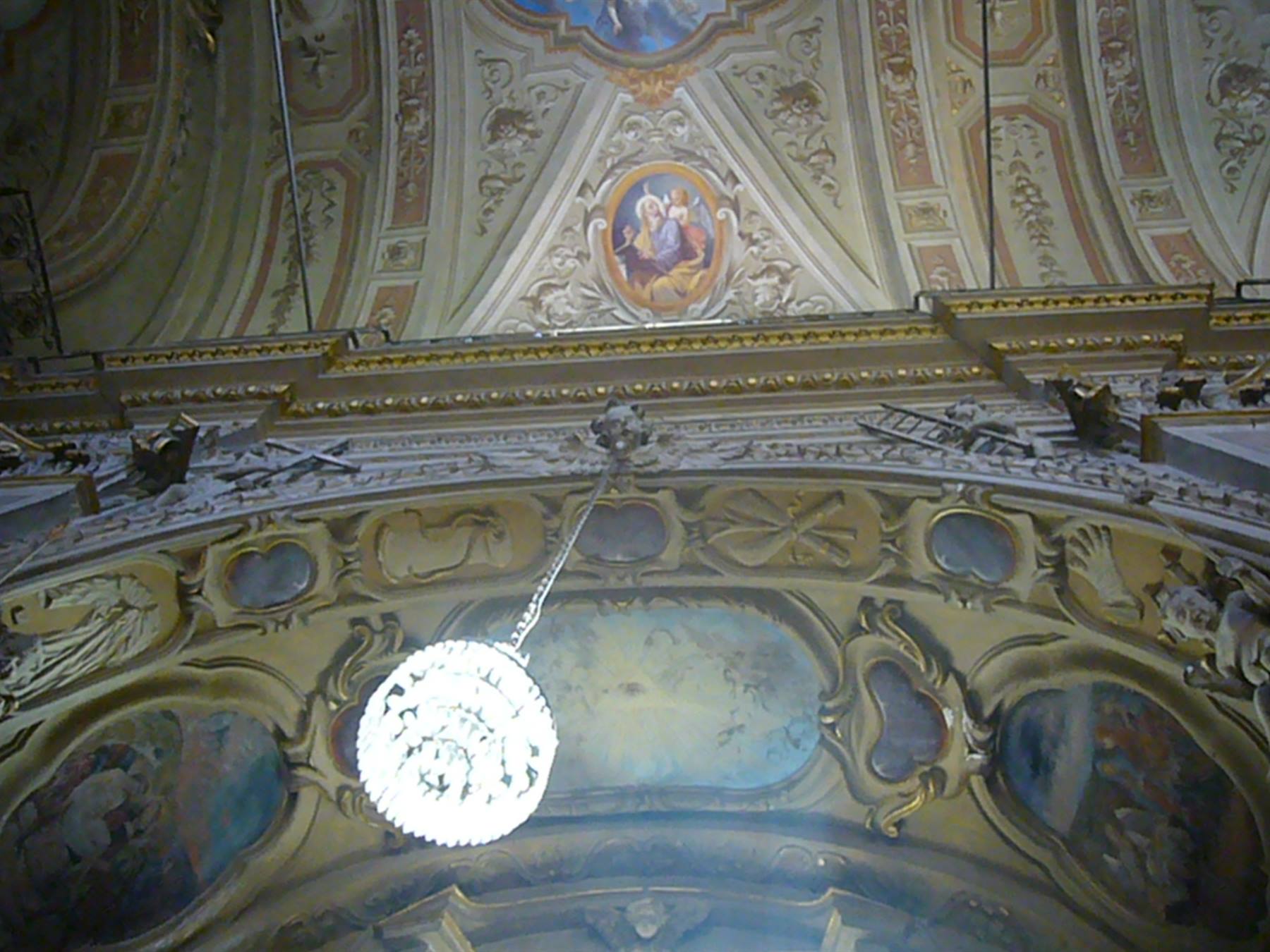 Soffitto di chiesa barocca con affreschi, stucchi dorati e lampadario in vetro acceso