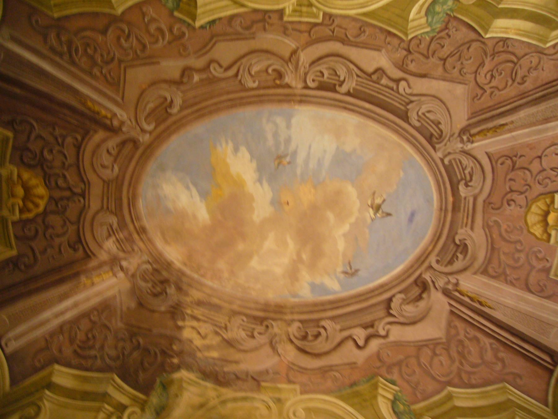 Affresco con nuvole e uccelli in cornice ovale barocca su soffitto