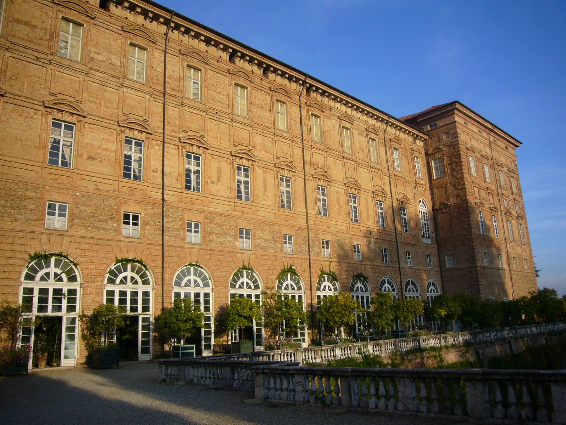 Facciata in mattoni della Reggia di Venaria con finestre ad arco e agrumi in vaso