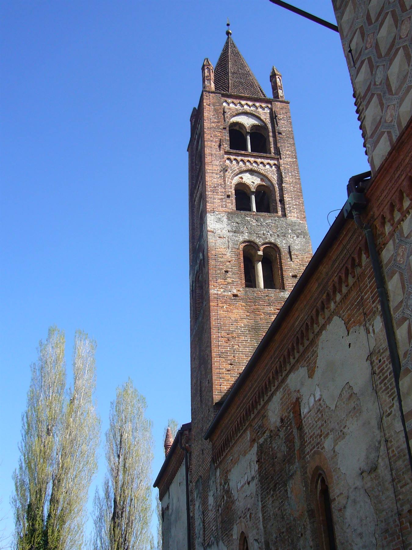 Campanile romanico in mattoni con bifore contro il cielo azzurro, Ontaneto vicino