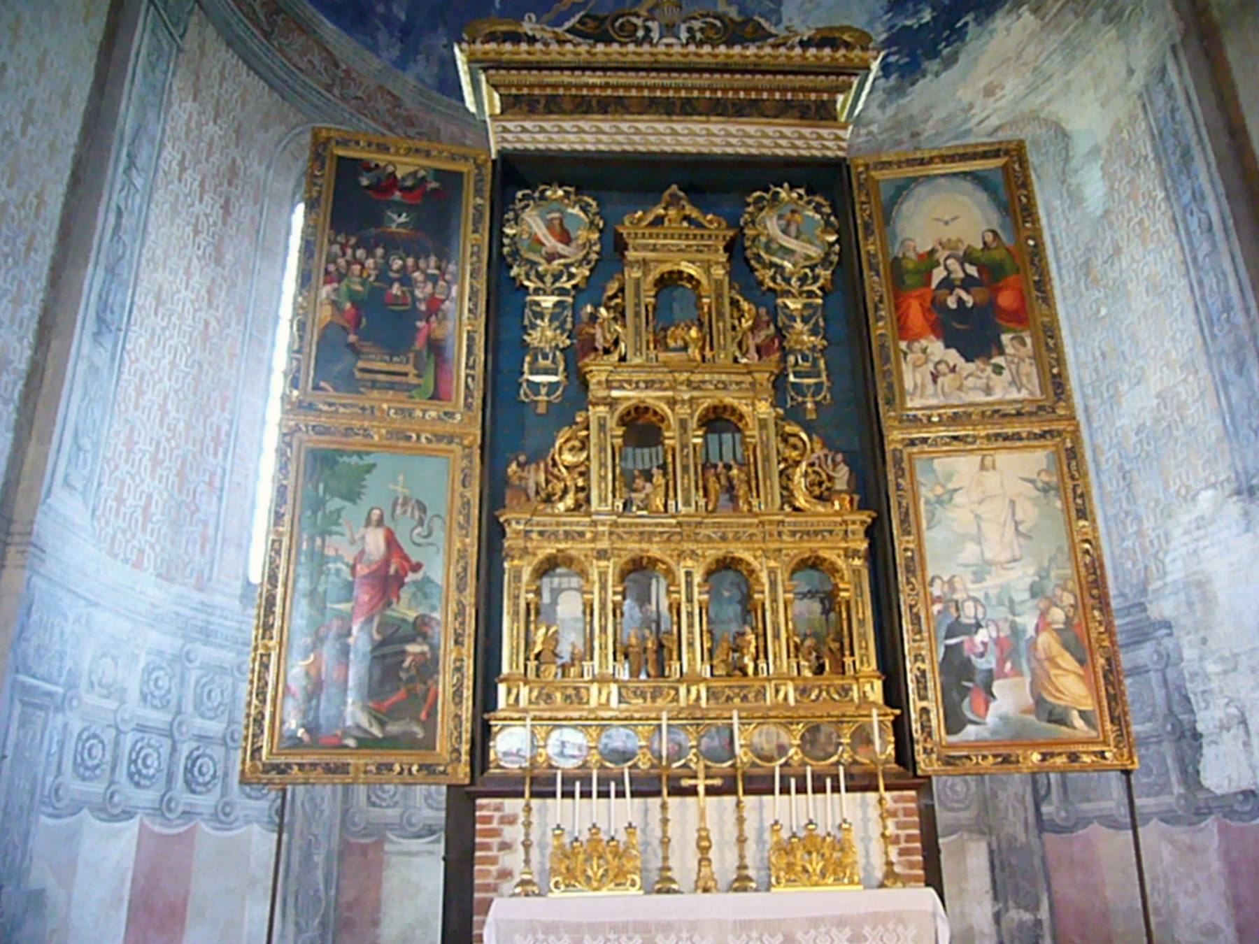 Ricco altare dorato con pale dipinte, dentro una chiesa affrescata