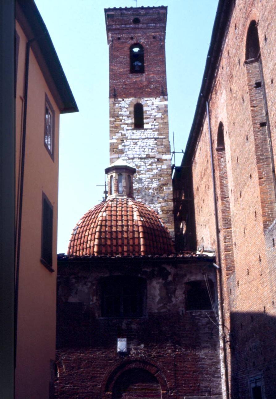 Campanile in pietra e mattoni con cupola di coppi tra edifici a Lucca