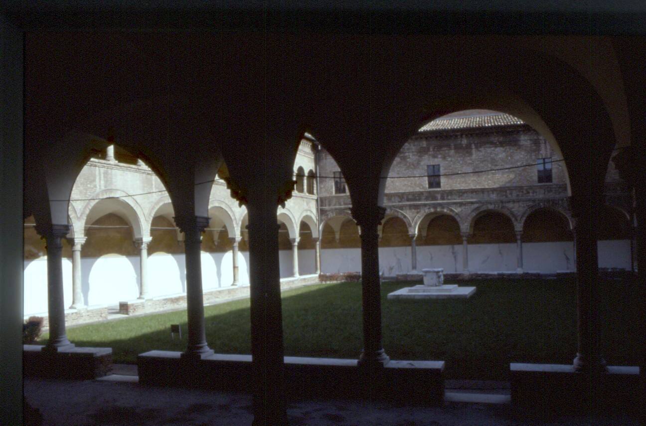 Chiostro con archi romanici e pozzo al centro del prato