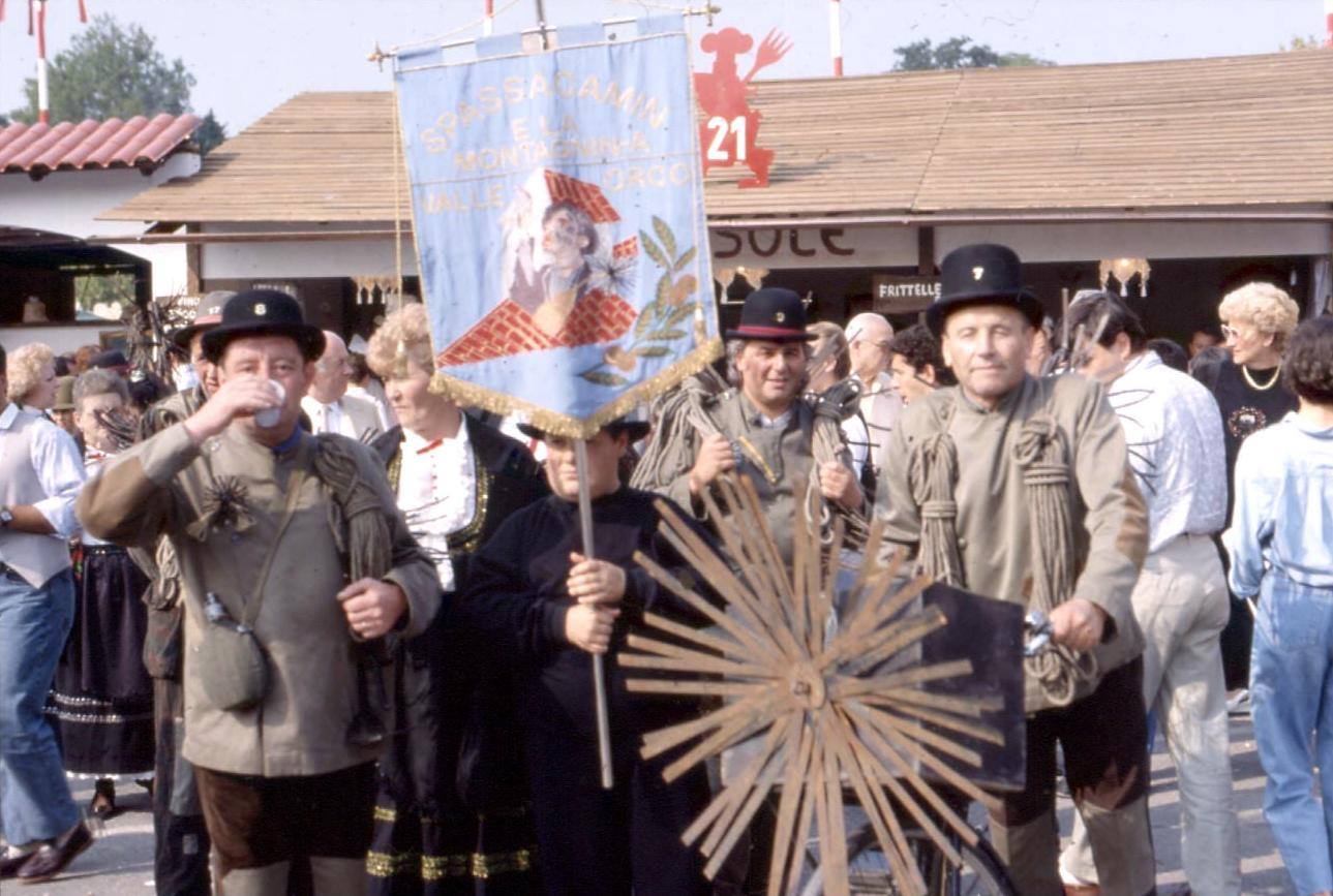 Uomini in costume tradizionale con stendardo e ruota di legno alla sagra paesana