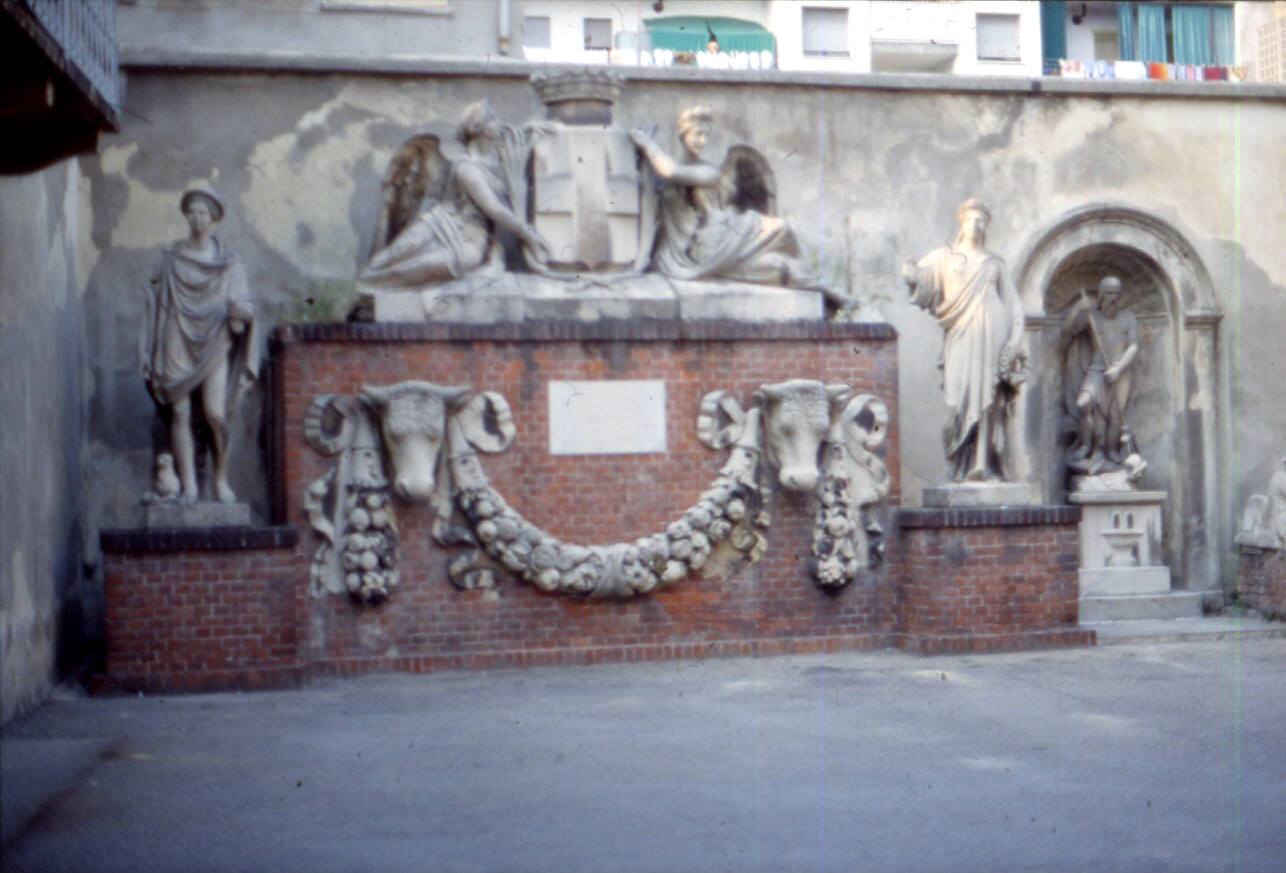 Statue di pietra e buoi scolpiti su muro di mattoni in cortile