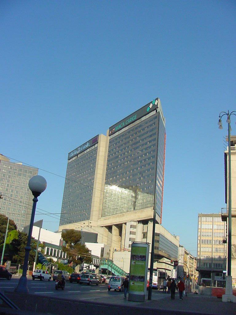 Grattacielo del Centro Direzionale di Napoli, traffico e pedoni sotto cielo azzurro