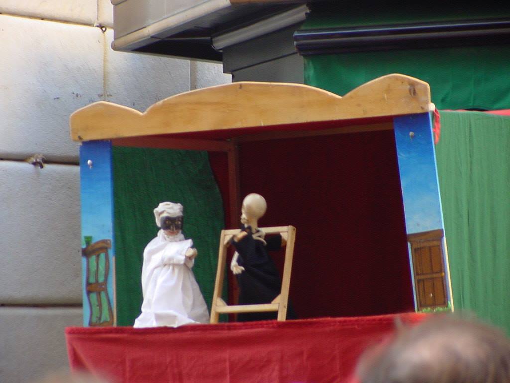 Marionetta bianca e scheletro di legno sul palcoscenico rosso di un teatrino di strada