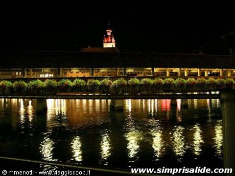 Il caratteristico "ponte dei fiori" di Lucerna, visto di notte, con sullo sfondo una torre delle mur