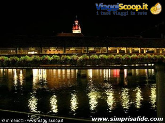 Il caratteristico "ponte dei fiori" di Lucerna, visto di notte, con sullo sfondo una torre delle mur