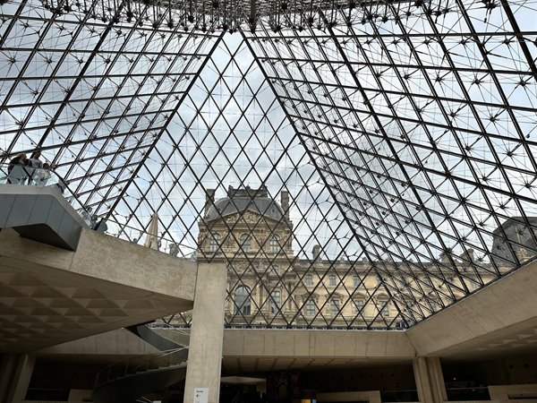 Sotto la piramide vetrata del Louvre, il tempo sembra sospeso.