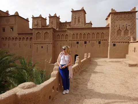 Turista appoggiata al muro di terra della kasbah di Skoura