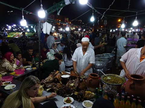 Cuoco con cappello bianco serve carne alla piazza Jemaa el-Fna, Marrakech, luci notturne