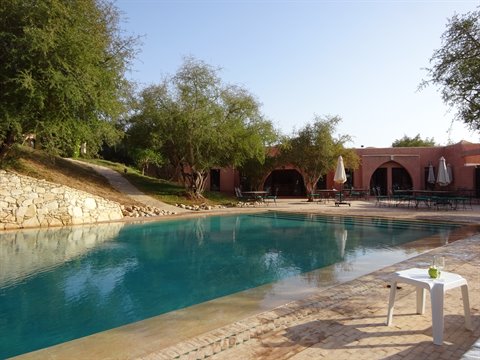 Piscina azzurra tra alberi e case in terra a Skoura