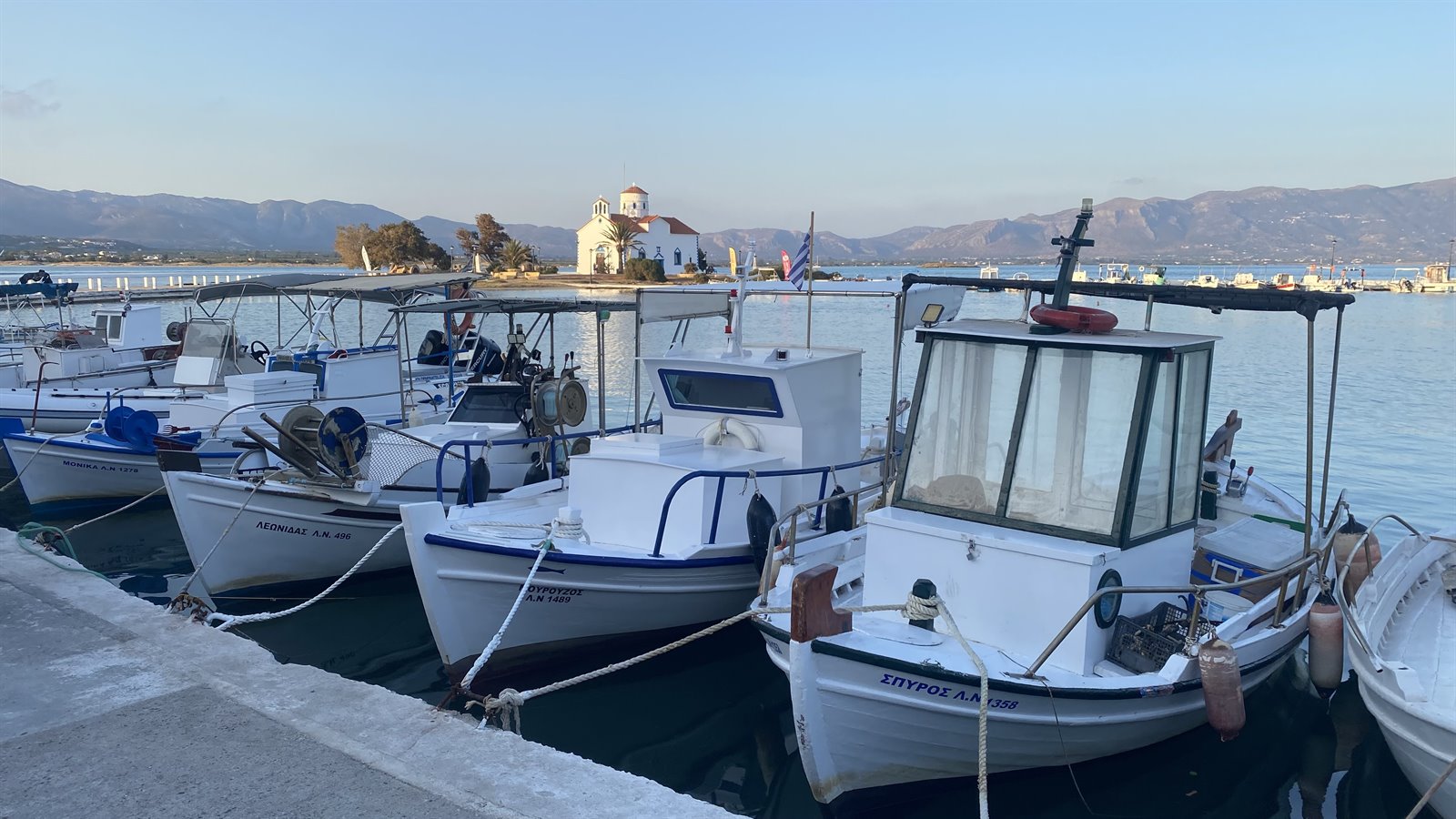 Barche bianche a riposo, chiesa sull'acqua: Grecia che sogna.