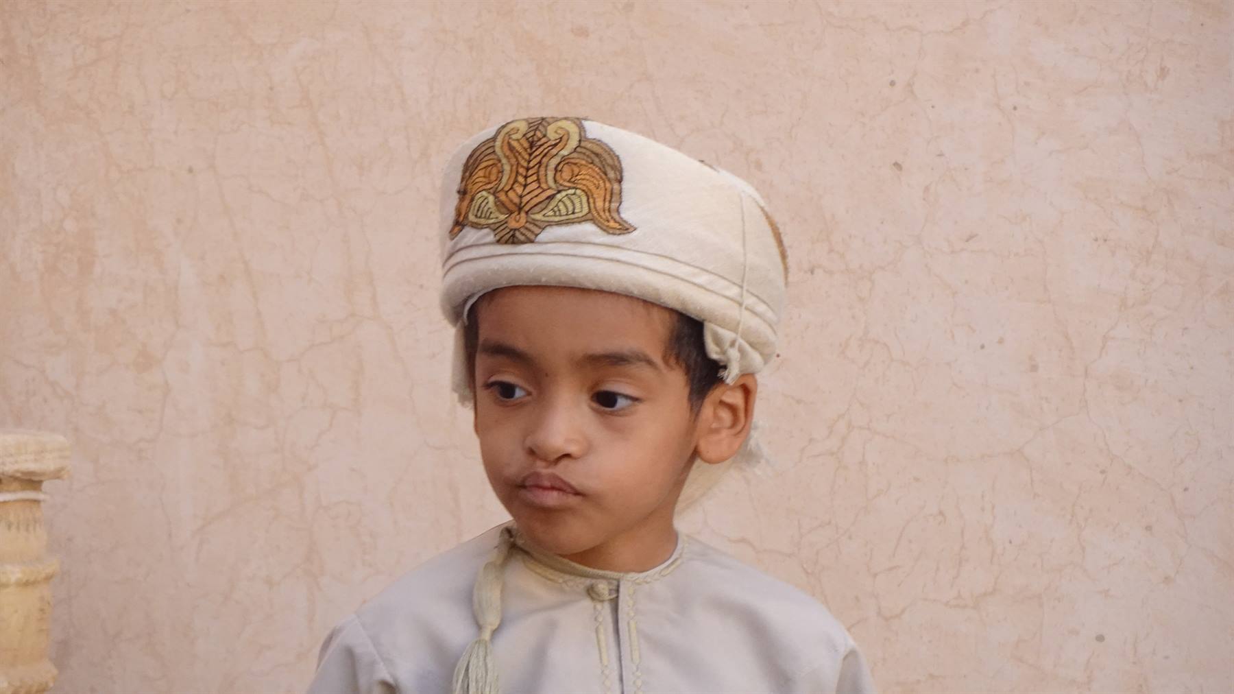 Sguardo serio e cappello ricamato: un piccolo principe d'Oman.