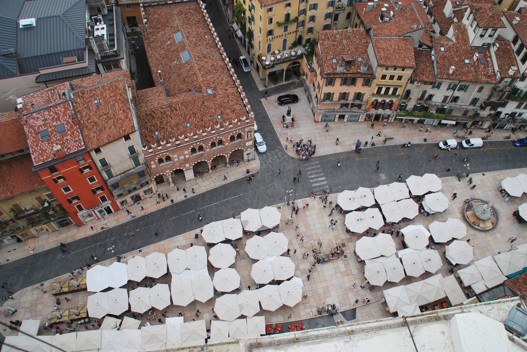 Piazza delle Erbe a Verona vista dall'alto, ombrelloni bianchi e palazzi gotici