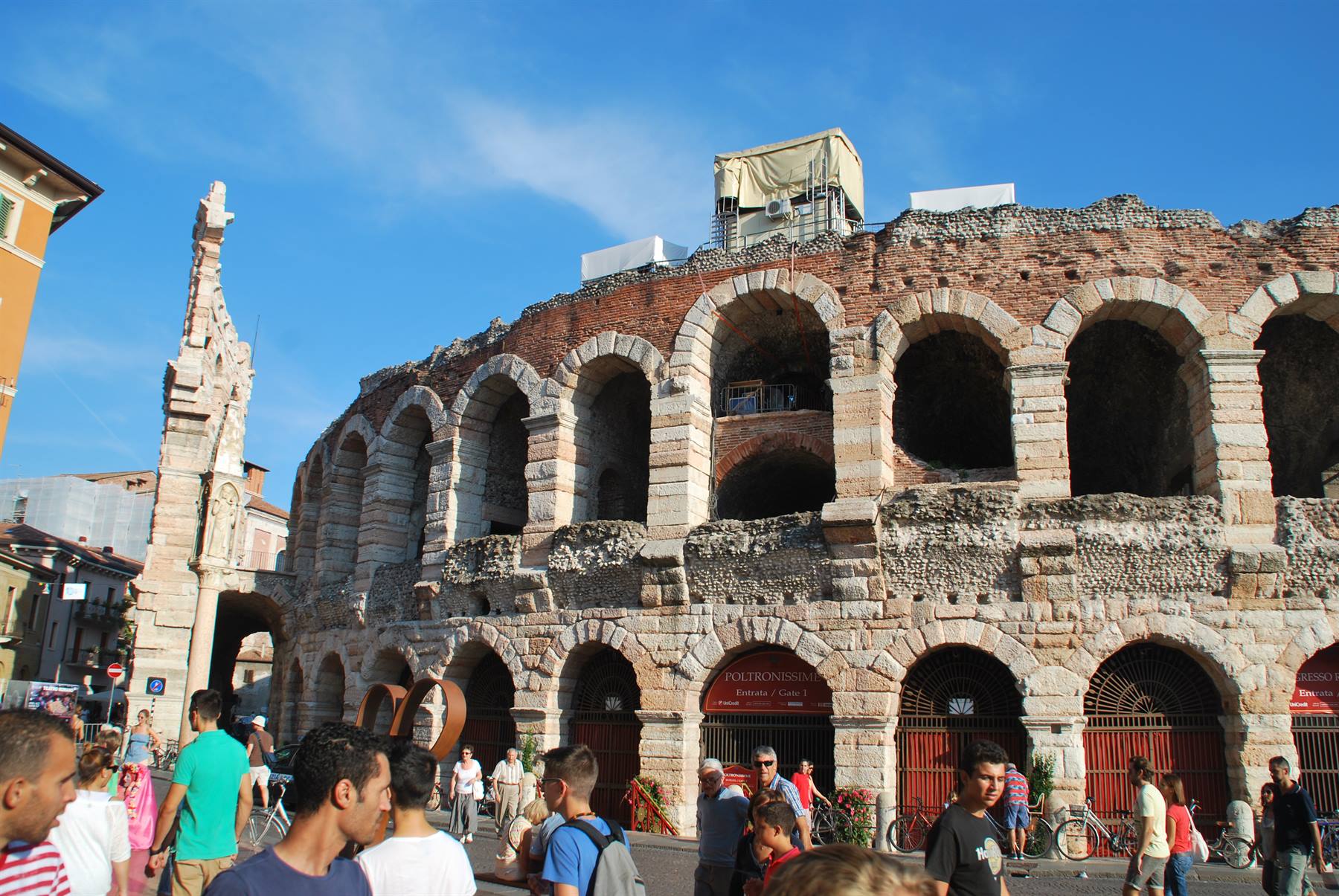Turisti passeggiano davanti ai grandì archi in pietra dell'Arena di Verona