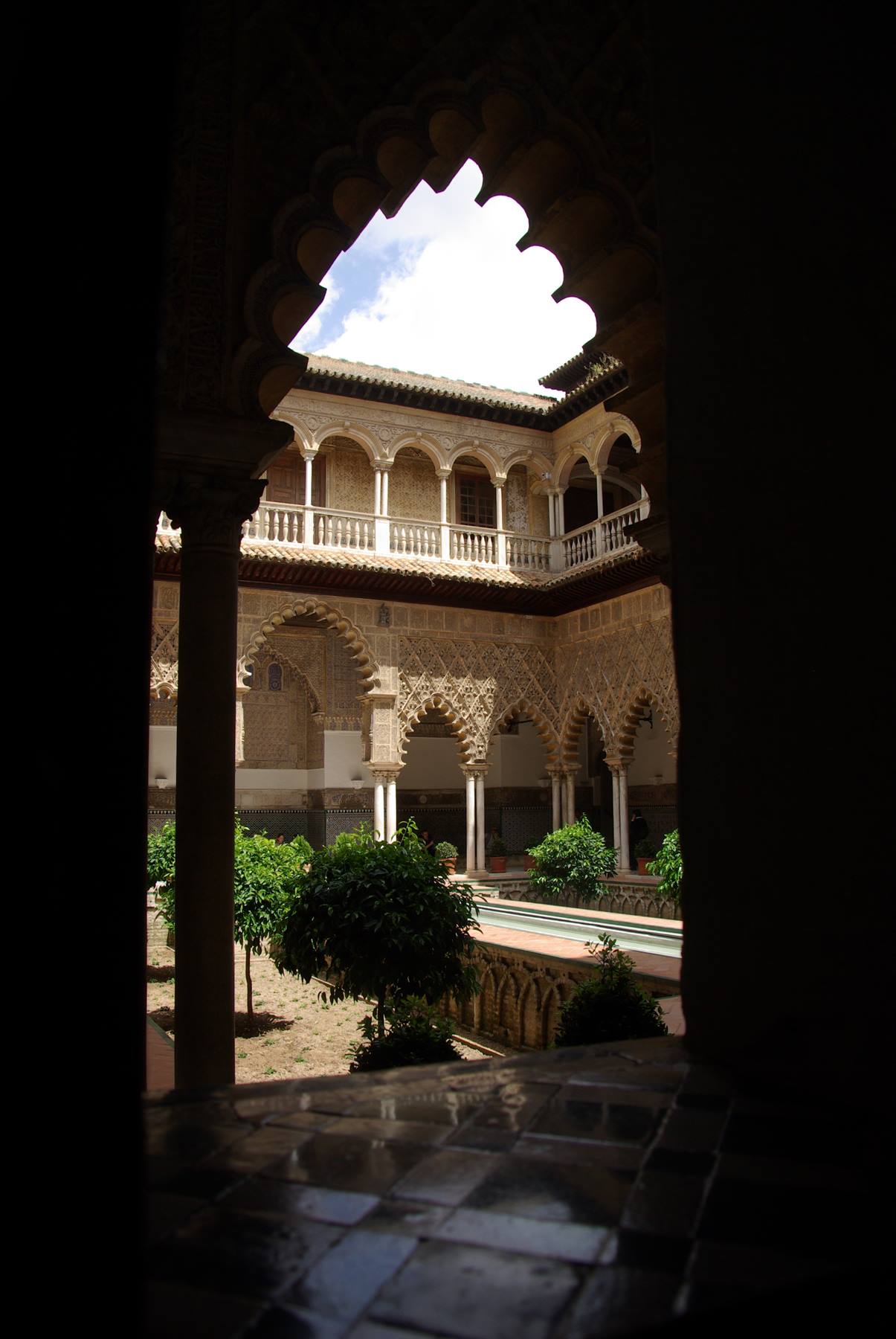 Arcate mudéjar e aranci nel chiostro dell'Alcázar di Siviglia, luce intensa