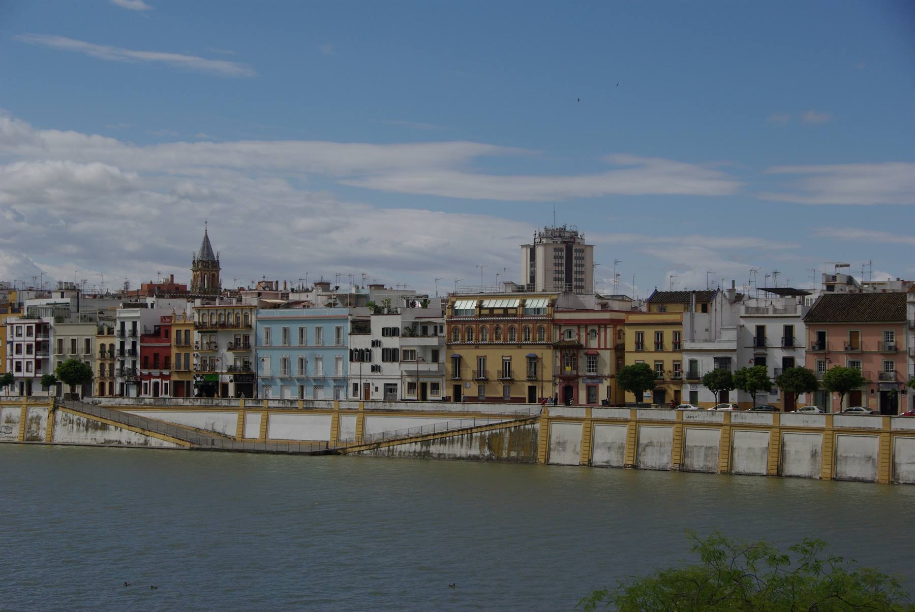 Case colorate lungo il Guadalquivir a Siviglia, sotto il cielo nuvoloso