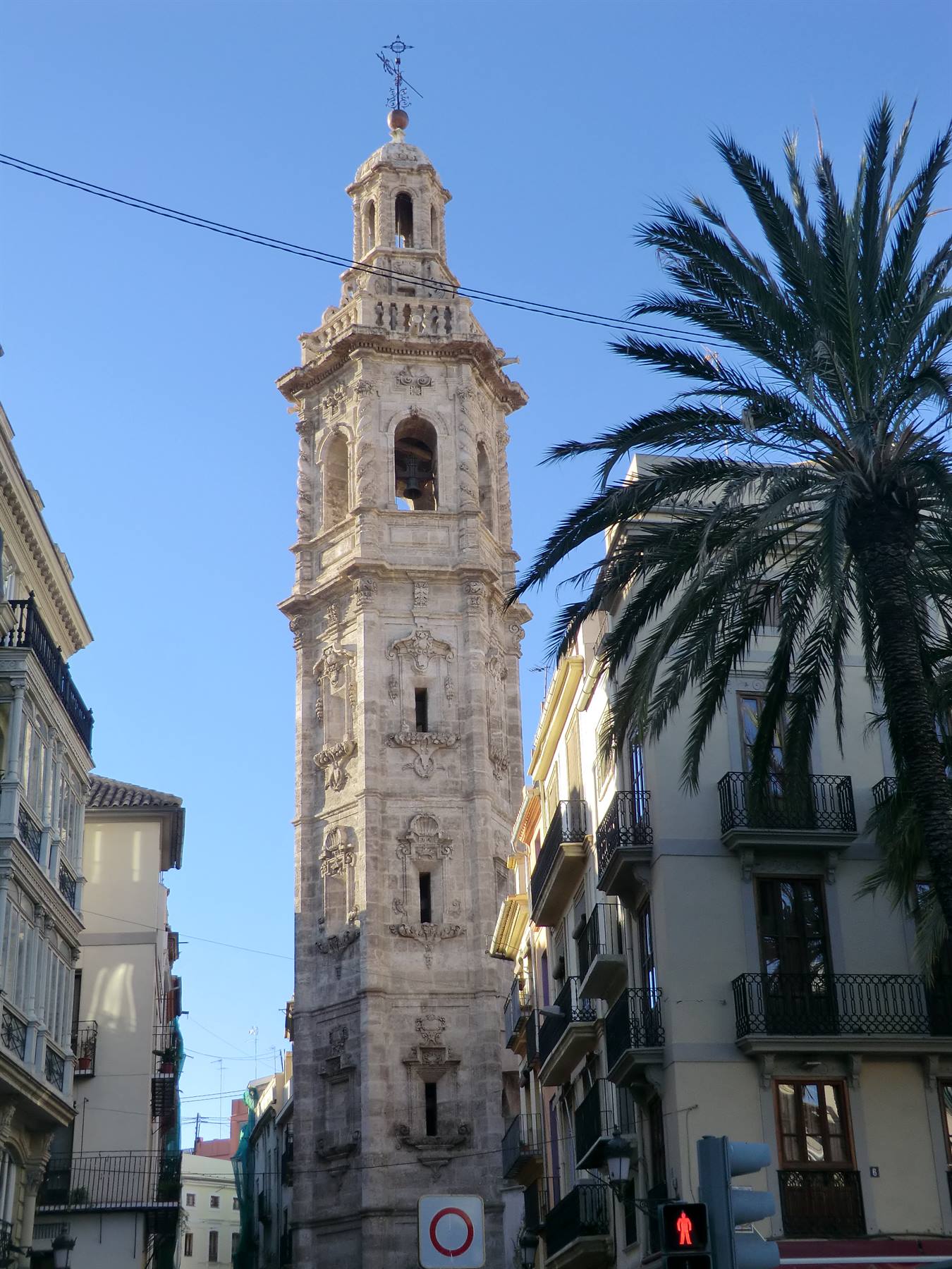 Torre barocca in pietra di Valencia accanto a palazzi con palme, luce diurna
