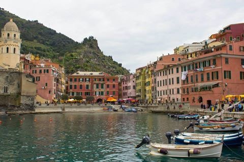 Barche ormeggiate al porto di Vernazza, case colorate sotto la torre campanaria