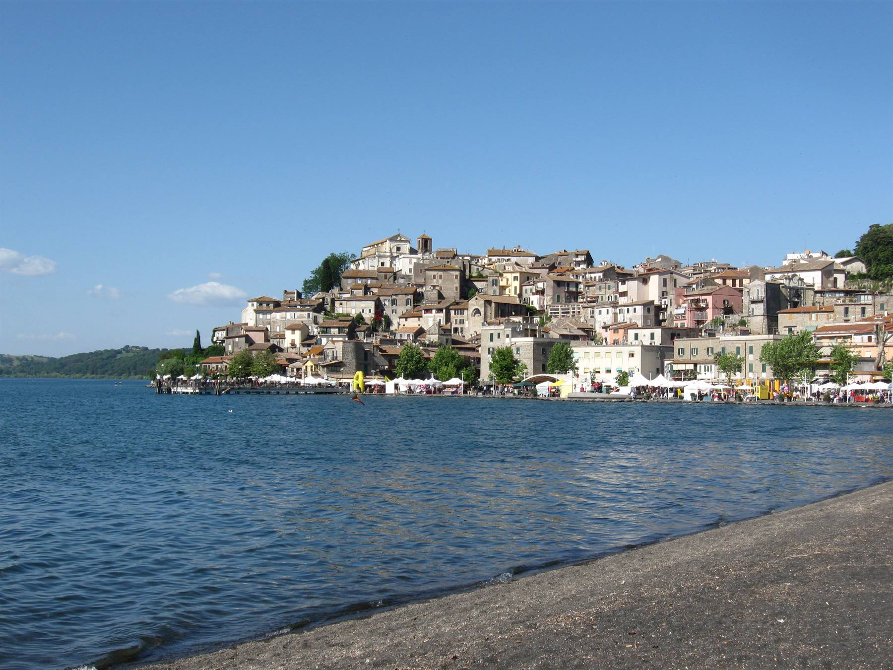 Anguillara Sabazia sul lago di Bracciano, case antiche sopra la spiaggia ombreggiate dagli ombrelloni