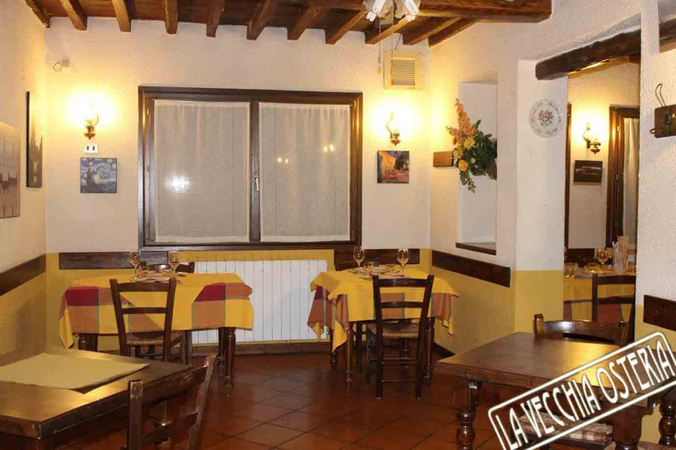 Sala rustica della Locanda La Vecchia Osteria, tavoli apparecchiati con tovaglie gialle