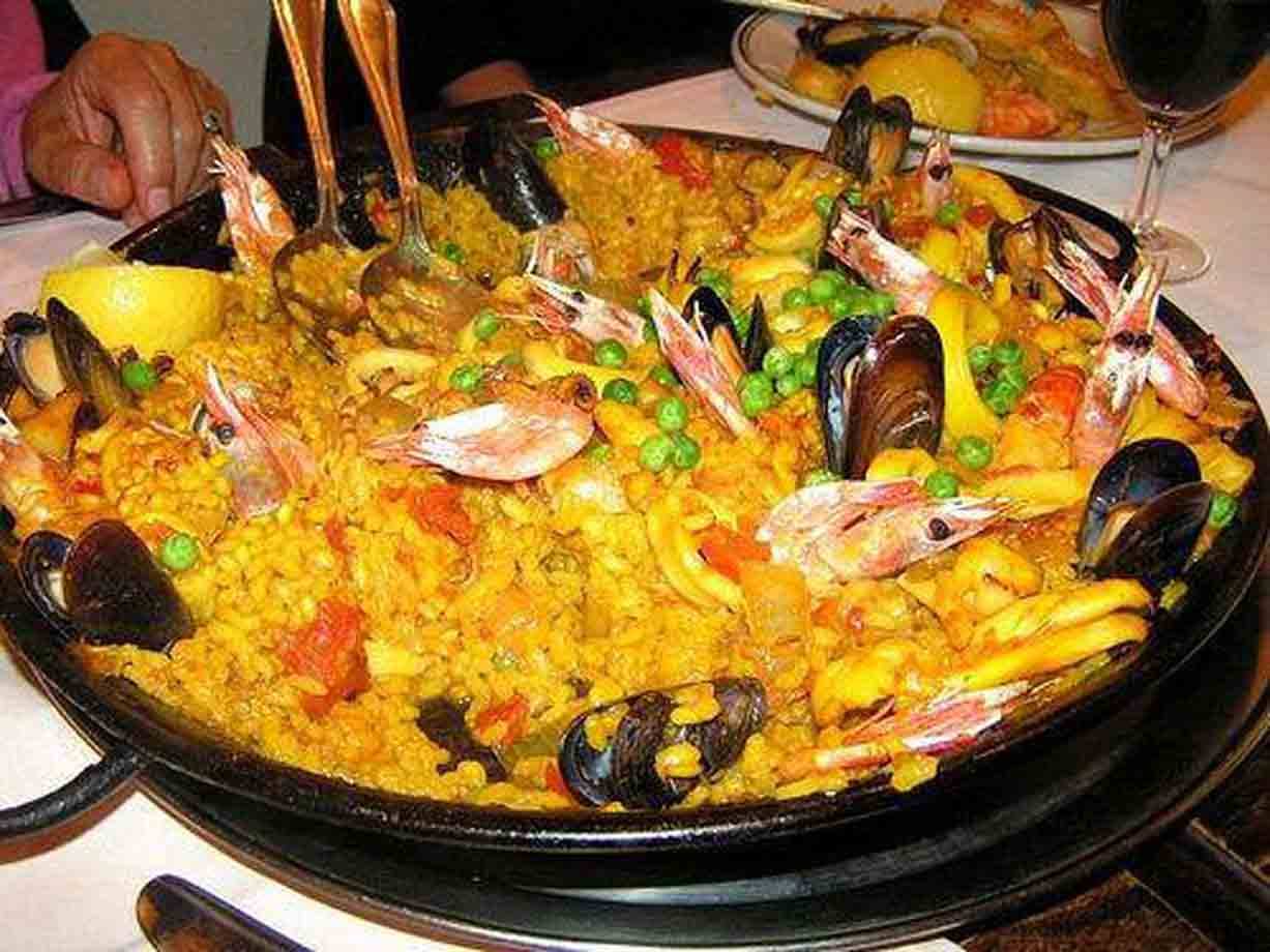 Paella di frutti di mare nella padella nera, con gamberi, cozze e piselli