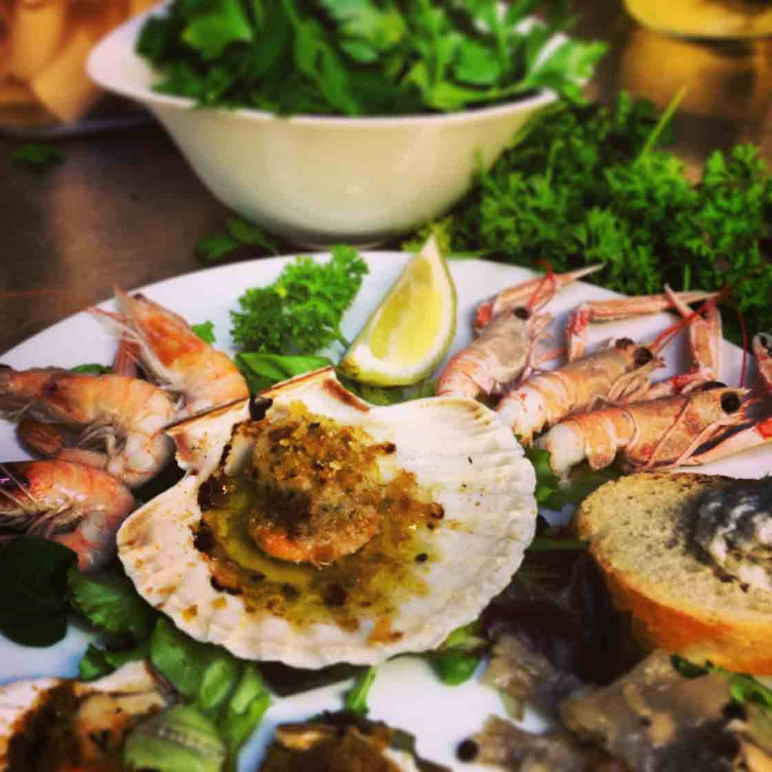 Piatto di capasanta al burro con scampi, gamberi, limone e prezzemolo fresco
