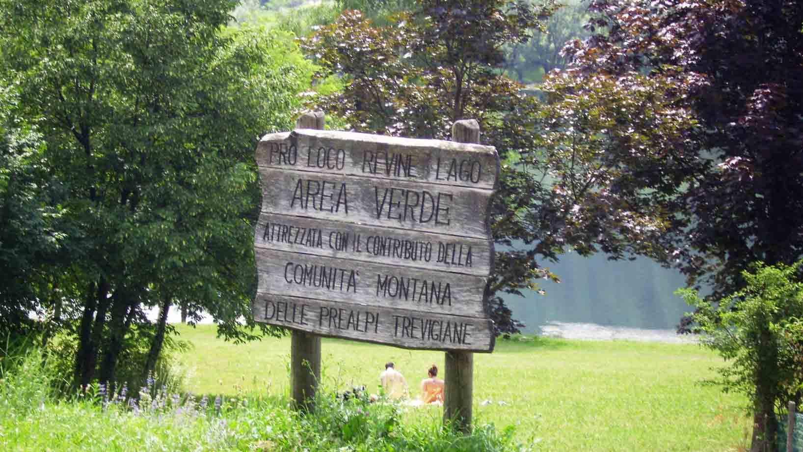 Cartello in legno Area Verde, prato e lago di Revine tra gli alberi