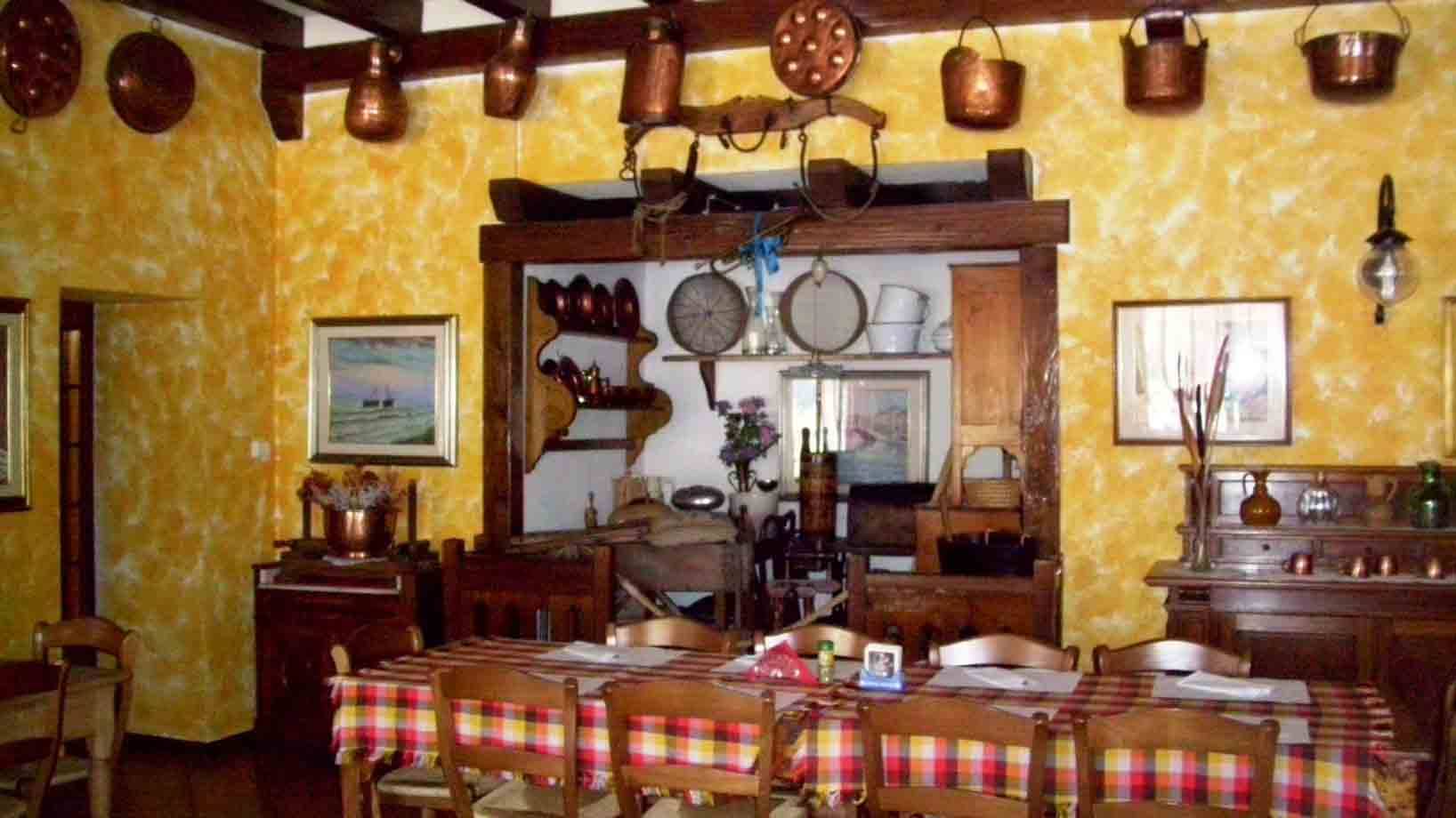 Sala rustica con pentole di rame appese, tavolo a tovaglia scozzese e mobili in legno