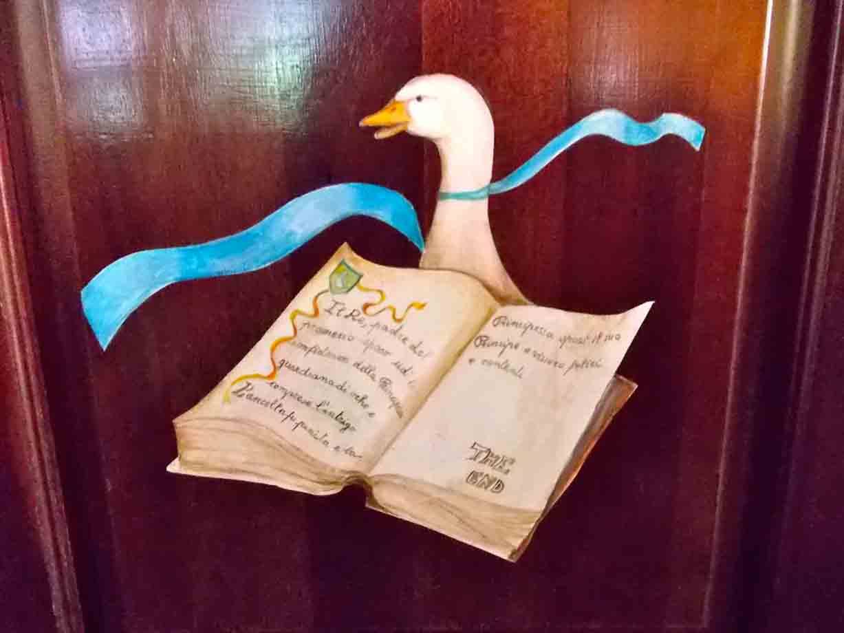 Dipinto su legno: un'oca bianca con nastro azzurro spiana un vecchio libro