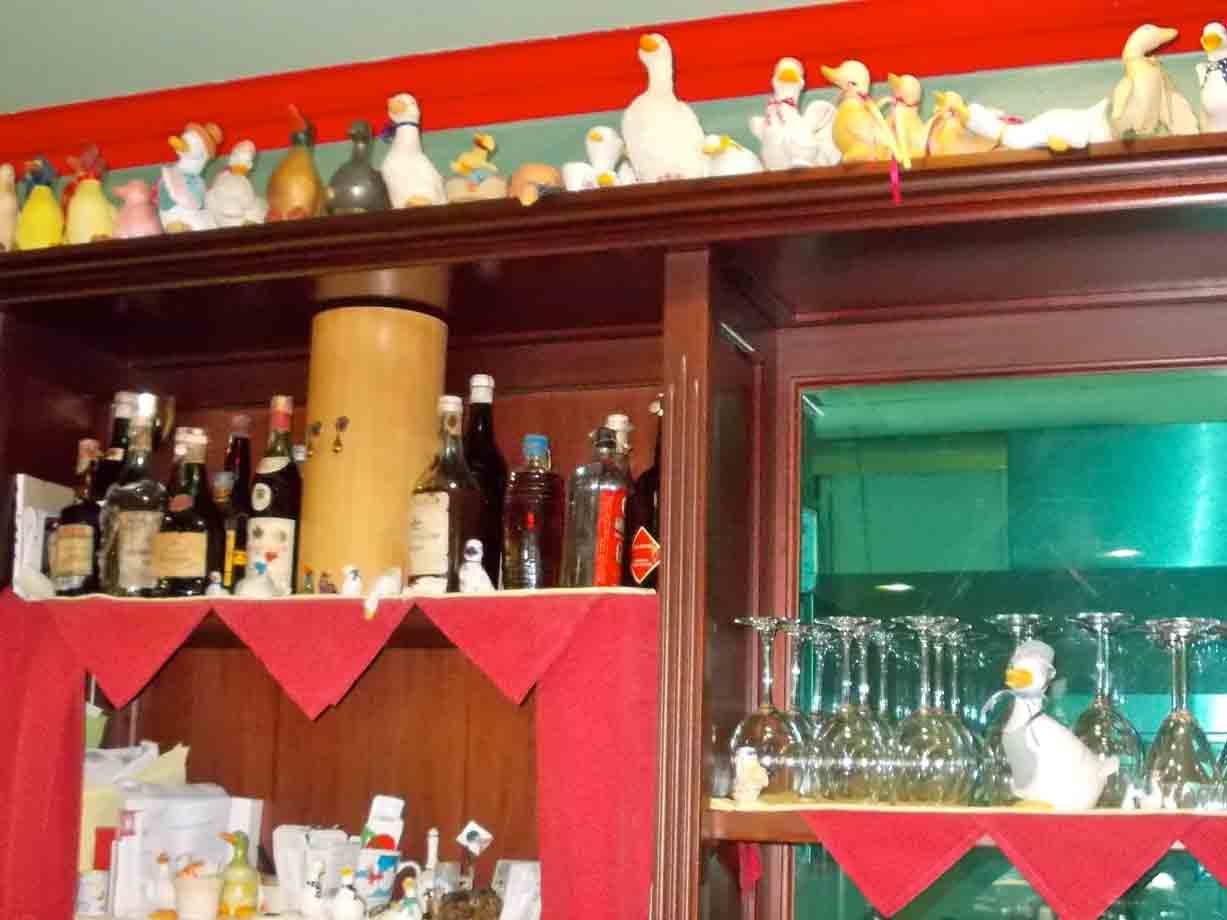 Molta in legno con bottiglie di liquore, bicchieri e paperelle di ceramica colorate