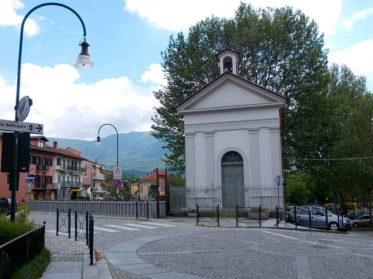 Chiesetta bianca con campanile al bivio, montagne e case sullo sfondo