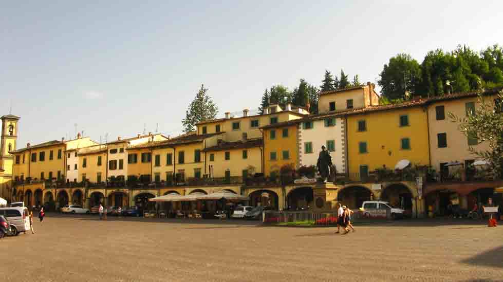 Piazza con statue e case colorate a Greve in Chianti, sotto cielo azzurro