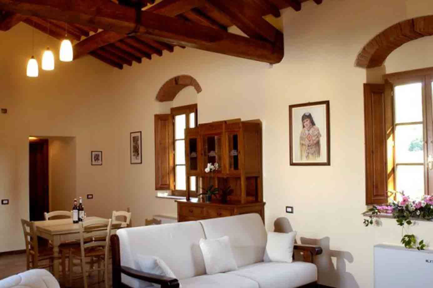 Soggiorno rustico con travi in legno, divano bianco, credenza e tavolo da pranzo
