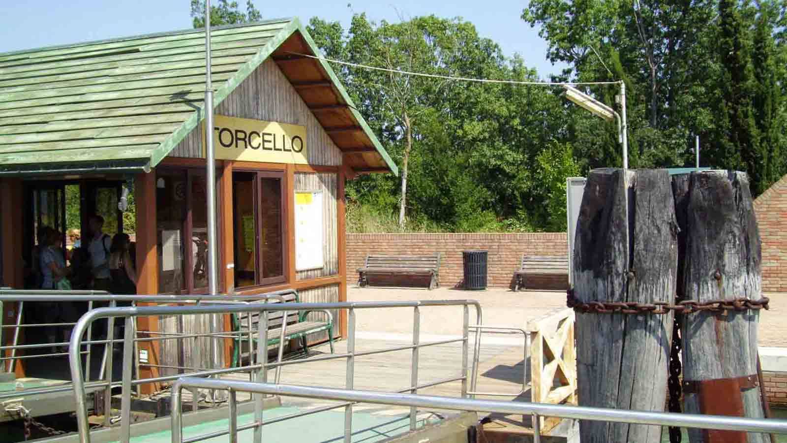 Imbarcadero di Torcello: chiosco in legno con tetto verde, pali di legno e passanti