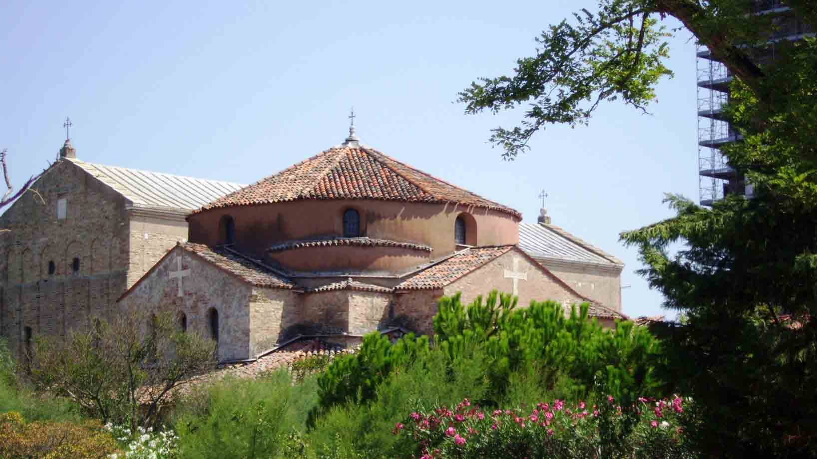 Torcello: la rotonda di Santa Fosca in mattoni tra alberi e fiori rosa