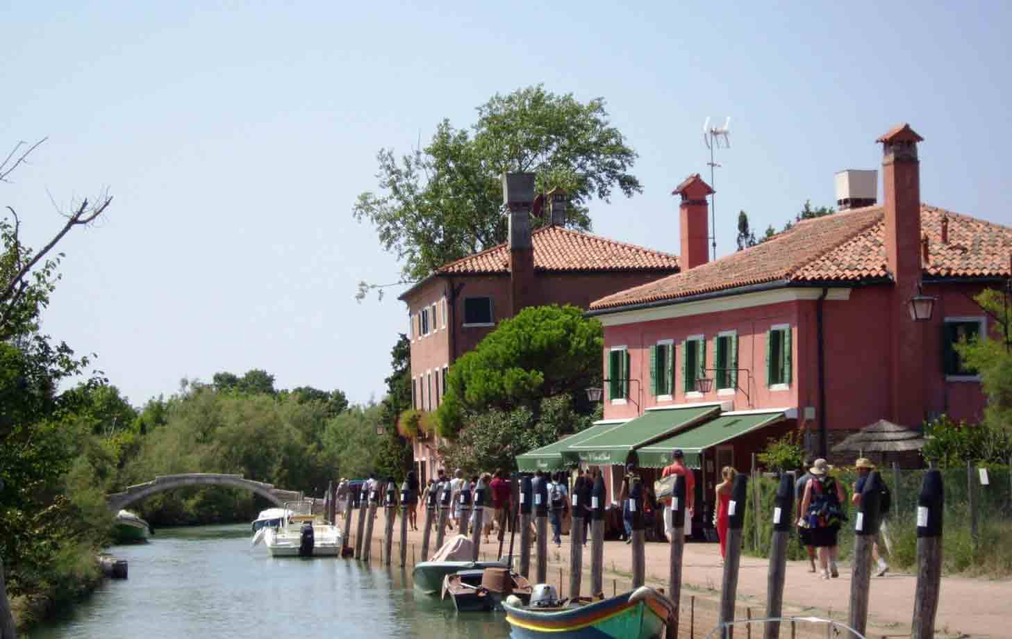 Turisti lungo il canale di Torcello, case rosse, barconi e ponte in mattoni