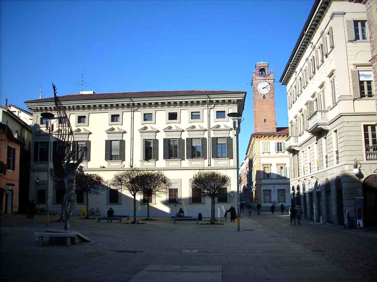Piazza Cavour a Vercelli, palazzo giallo e torre civica con orologio, cielo blu