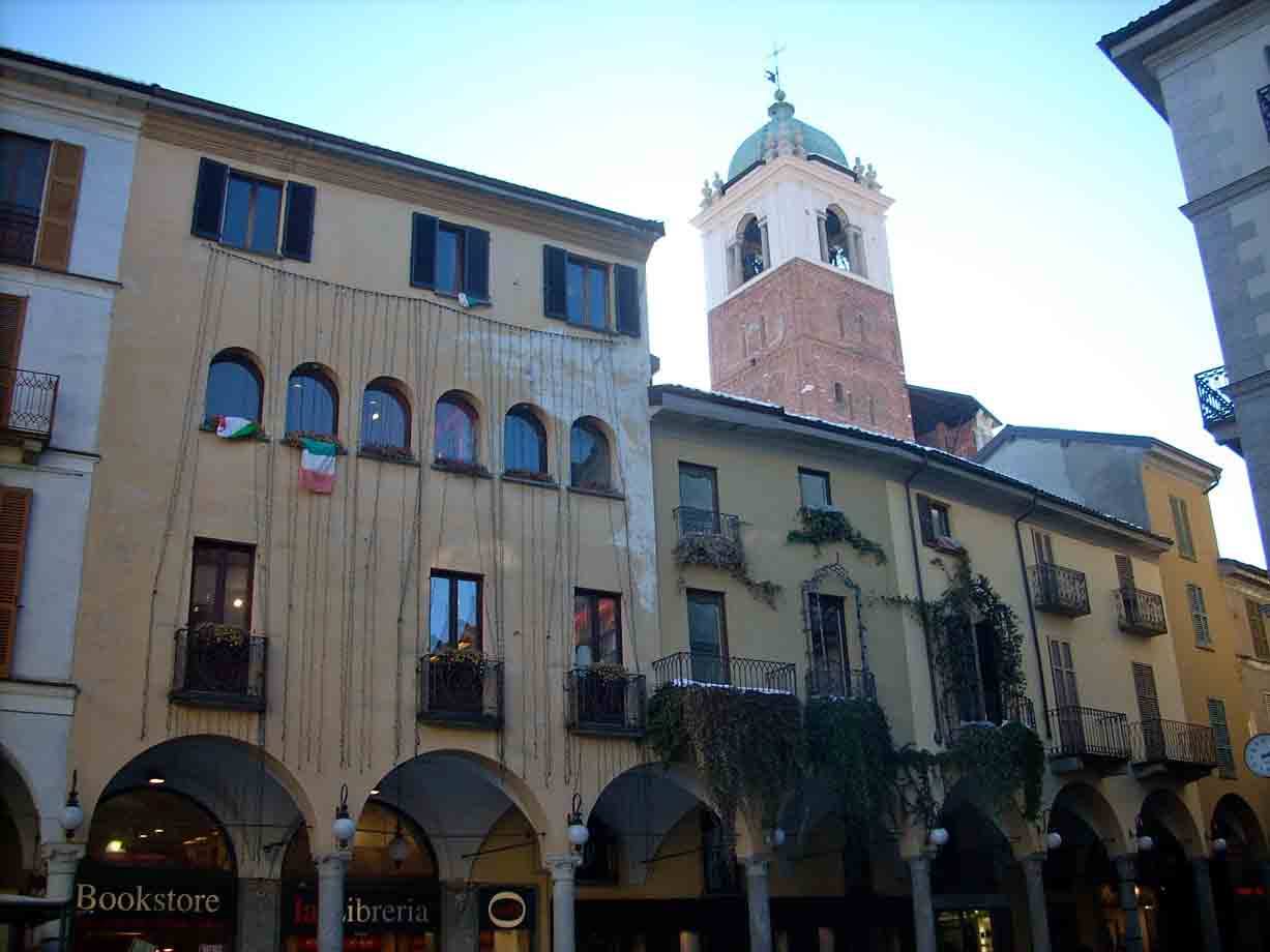 Portici con bookstore, palazzi gialli e campanile in mattoni con cupola verde