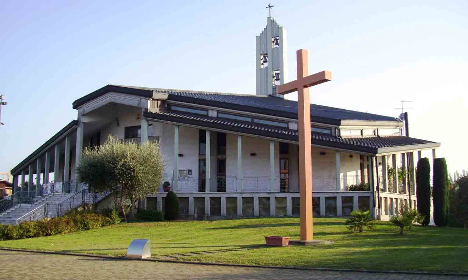 Chiesa moderna con campanile e grande croce di legno sul prato