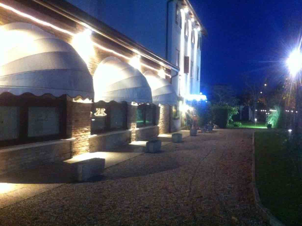 Facciata di ristorante di notte con tende da sole e luci sui mattoni