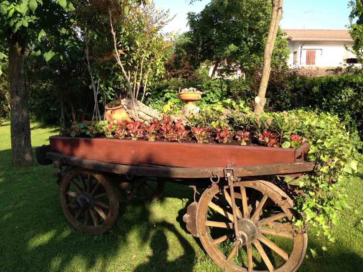 Carro di legno con ruote a raggi, trasformato in fioriera in un giardino