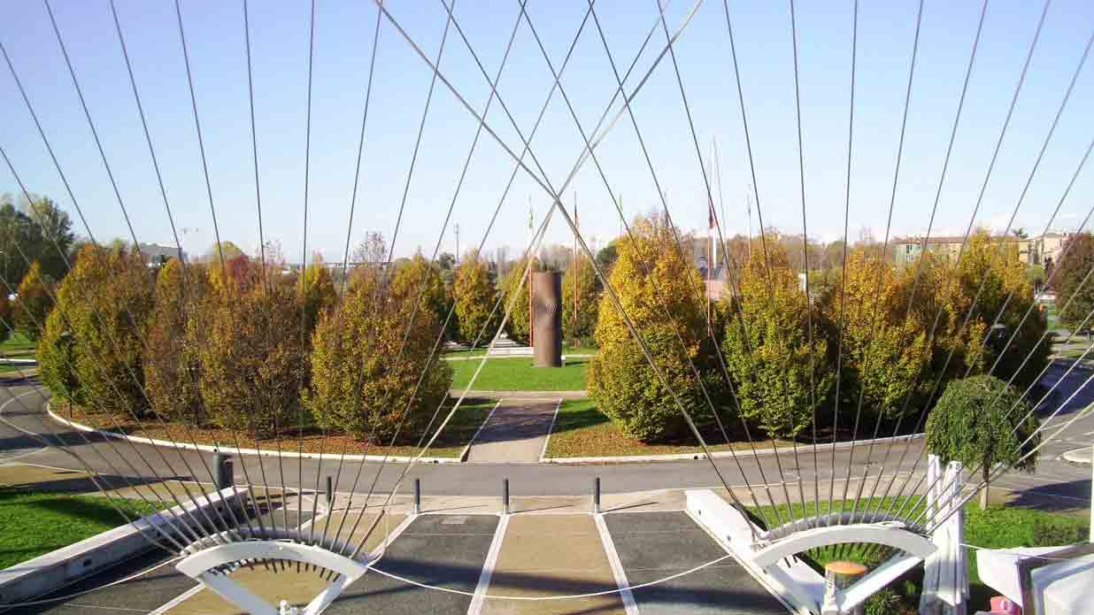Cavi d'acciaio di un ponte strallato bianco su parco con alberi autunnali